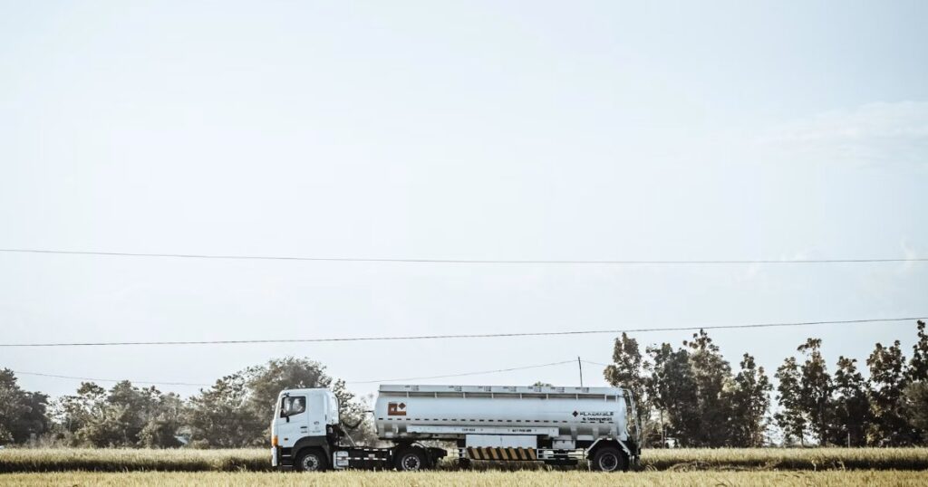 White and black semi truck parked on a green grass field